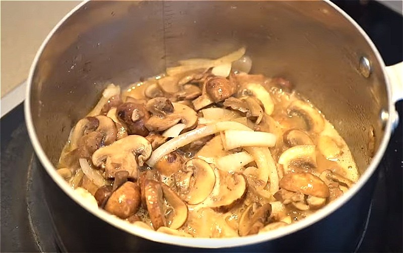 Слегка обжарьте лук и грибы на сливочном масле.